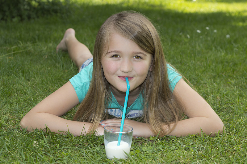 女孩躺在草地上用吸管喝牛奶图片下载