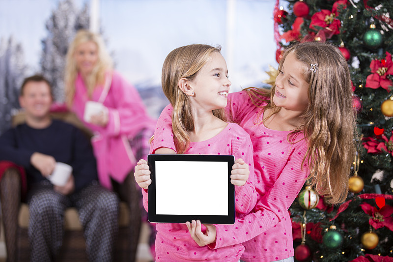小女孩兴奋地打开数码平板电脑的圣诞礼物。空白屏幕。图片下载