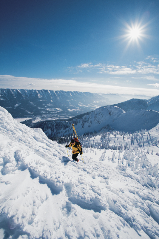 滑雪者扛着滑雪板爬上崎岖的雪山图片下载
