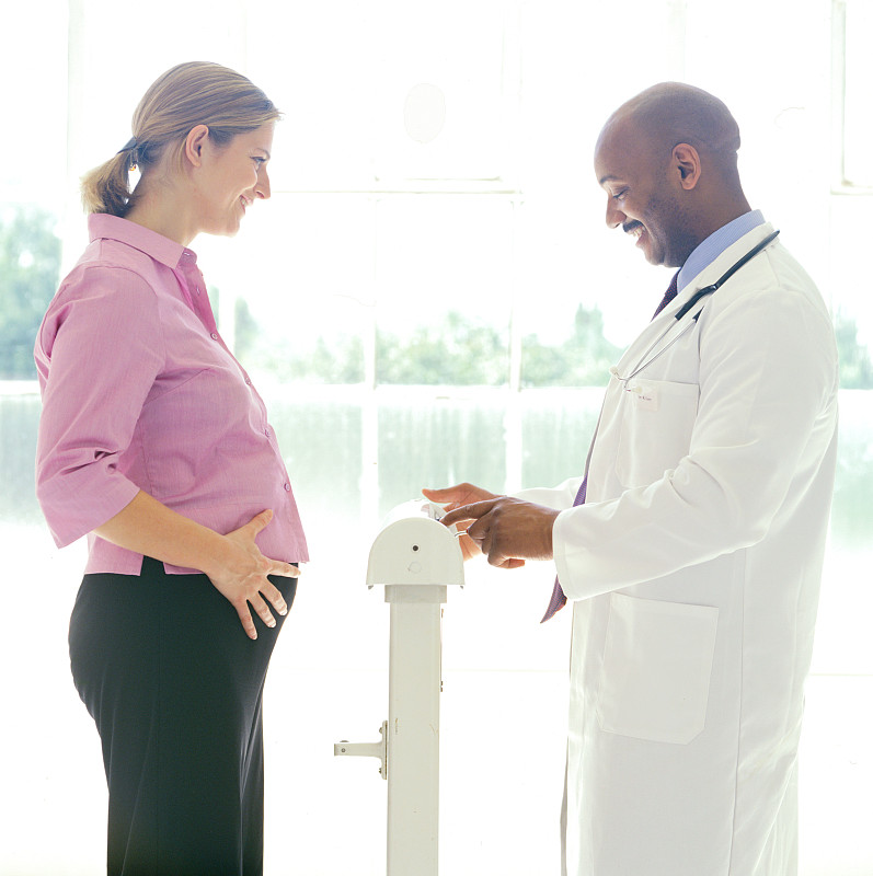一名年轻孕妇的肖像，她正在接受医生的体重检查图片下载