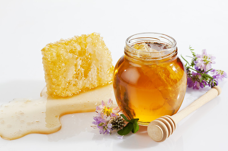一杯蜂蜜，蜂房，蜂蜜勺和野花图片素材