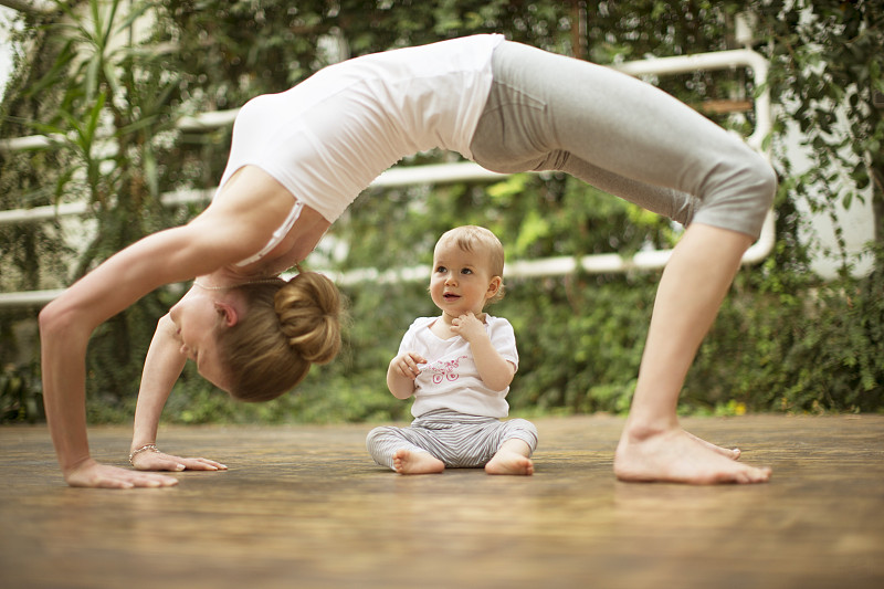 女人做瑜伽锻炼，而婴儿看着她图片下载