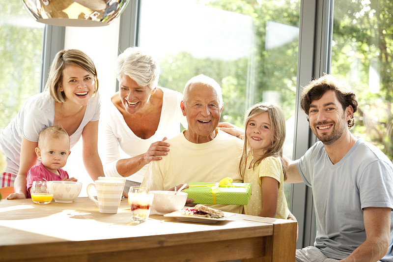 幸福的大家庭肖像与礼物在早餐桌上图片下载