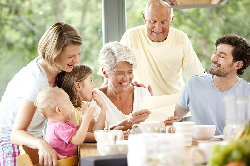 快乐的孙女和她的家人在早餐桌上读信图片下载