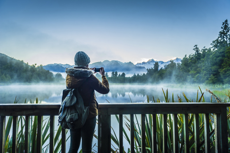一名身穿外套的西班牙妇女在拍摄雾蒙蒙的山湖图片素材