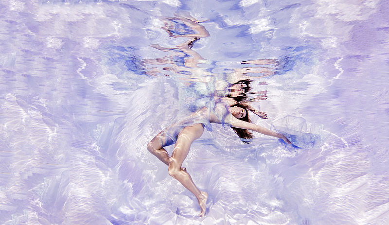 水下的观点，女人披着薄纱织物，浮向水面图片下载