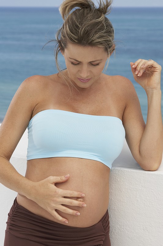 一个孕妇触摸她的腹部的特写图片下载