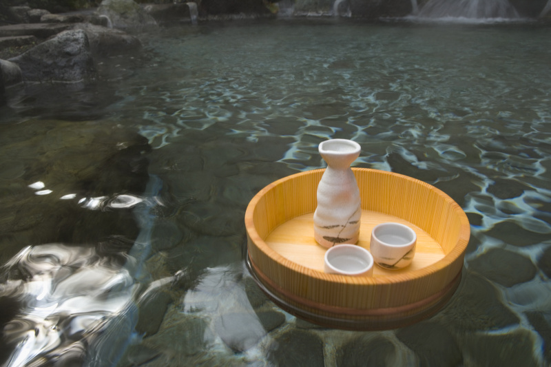 清酒酒瓶和杯子漂浮在一个日本公共浴池上，温泉，高角度观赏，日本图片下载