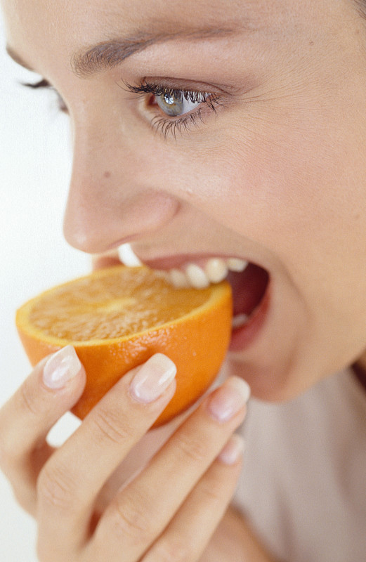 Smiling woman eating an orange图片素材