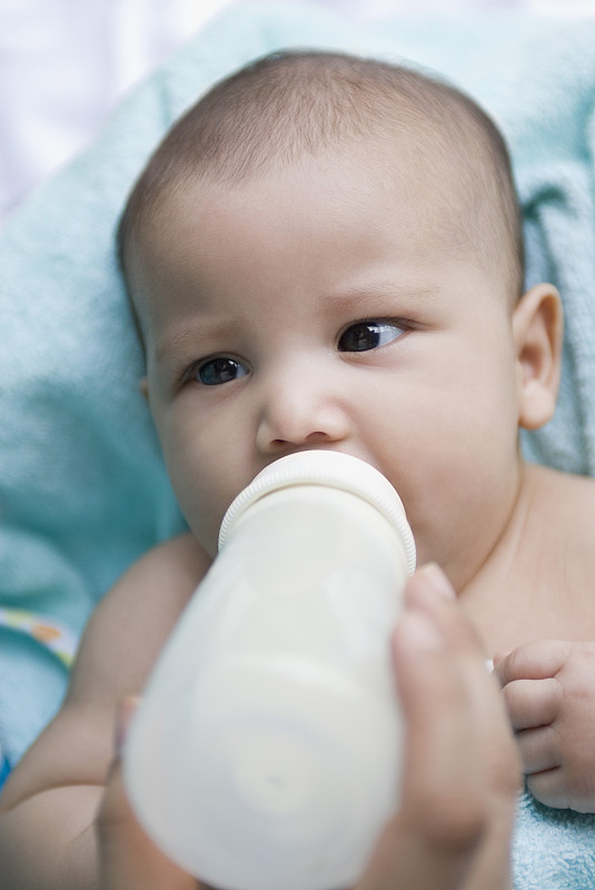 一个人的手用奶瓶喂一个男婴的特写图片下载