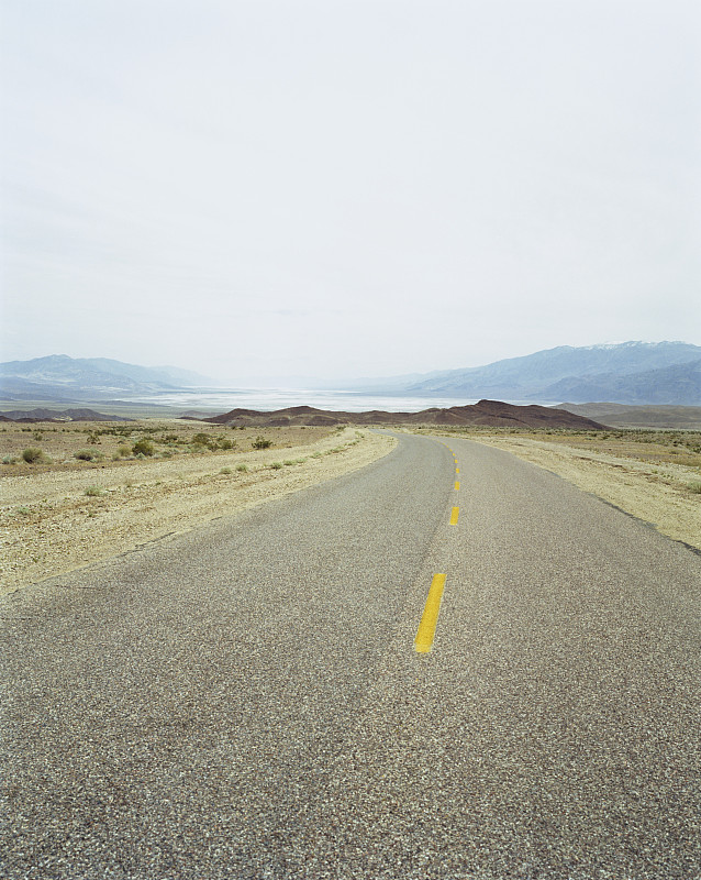 加州死亡谷的沙漠公路，地平线上有山脉图片素材