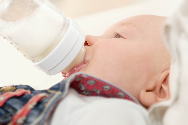 一个婴儿喝着一瓶牛奶，很放松图片下载