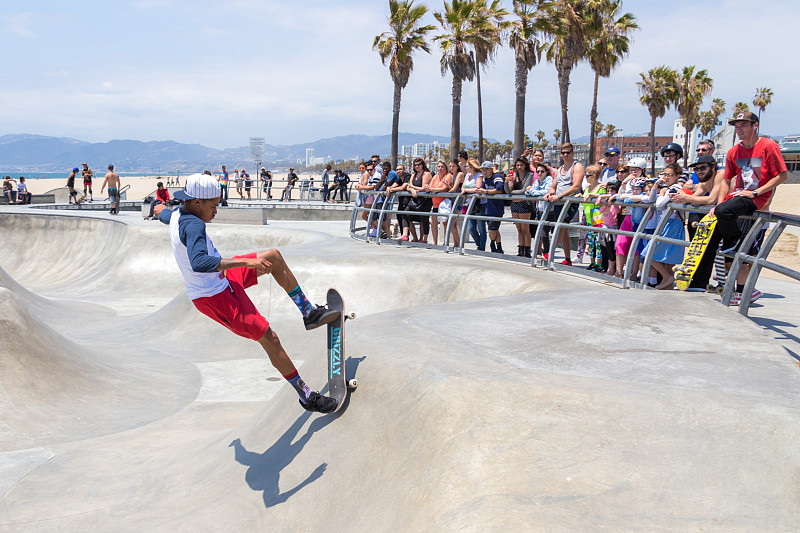 滑板男孩在加州洛杉矶威尼斯海滩的滑板公园练习。威尼斯海滩是洛杉矶最受欢迎的海滩之一图片素材