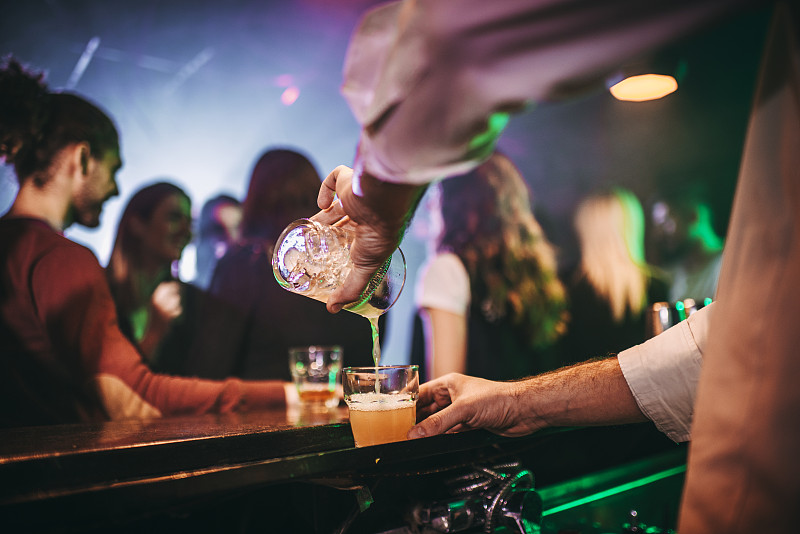 酒吧里用摇酒器将饮料倒入小酒杯的酒保图片下载