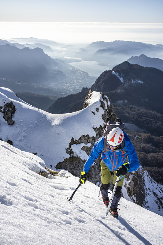 意大利莱科，一名登山运动员正在攀登一座白雪皑皑的山峰图片下载