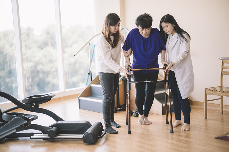 康复的概念。亚洲华裔女医生和护士在康复病房帮助老人与walker图片下载