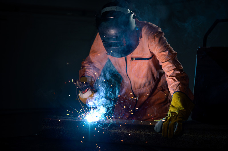 在管道工作中带保护面罩和火花的焊接金属的工业焊工图片下载