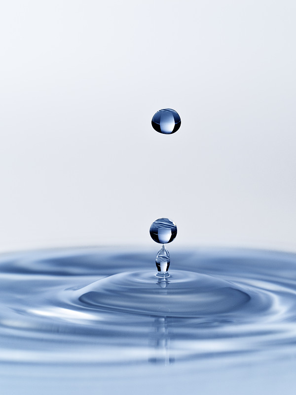 一组水滴悬在空中，落在蓝色背景的水面上。图片素材