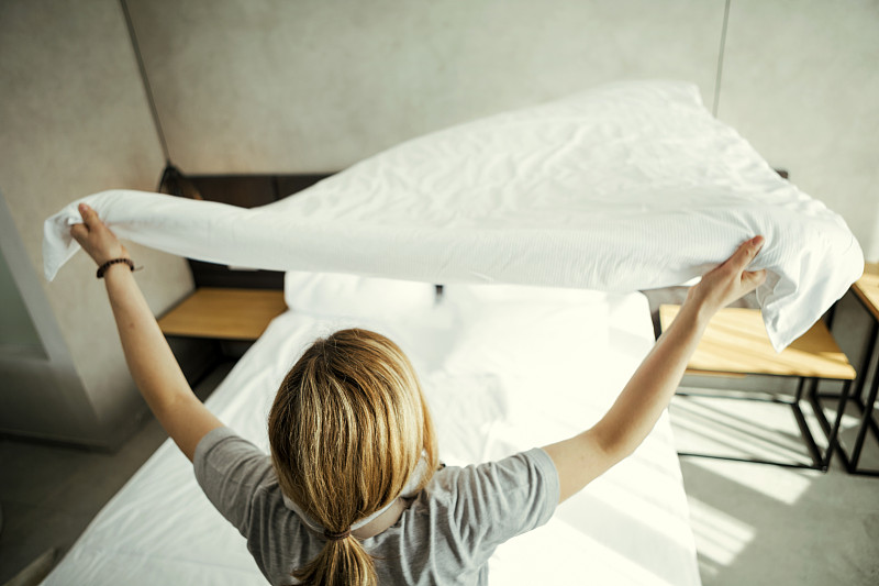 在酒店里用空气整理床上用品的女保洁员图片下载