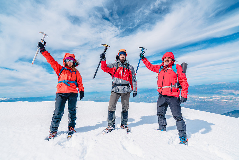 冬季，高山登山队正手持冰镐站在高海拔的山峰上图片素材