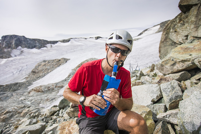 登山者从装有过滤器的瓶子里喝水。图片下载