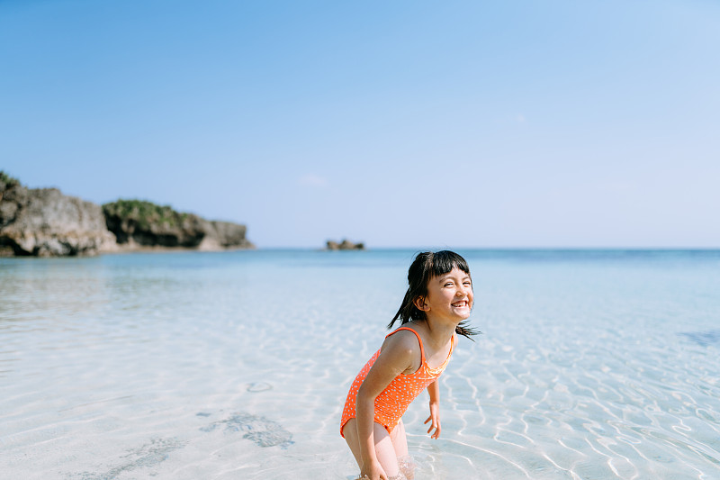可爱的欧亚女孩玩在热带海滩水，冲绳，日本图片下载