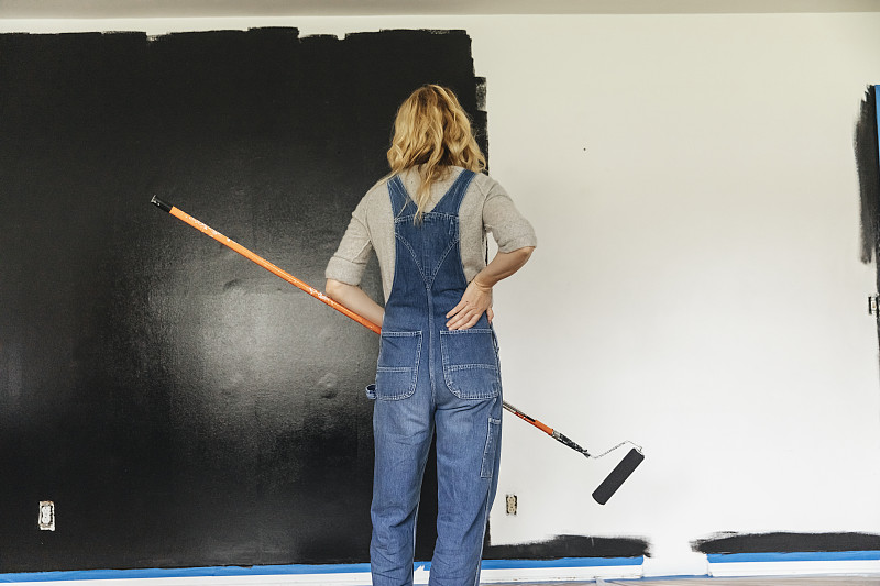 女人站在家里看着粉刷的墙图片下载