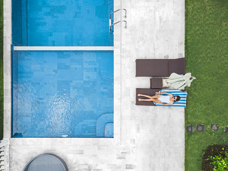 鸟瞰图迷人的女人附近的游泳池在度假村图片素材