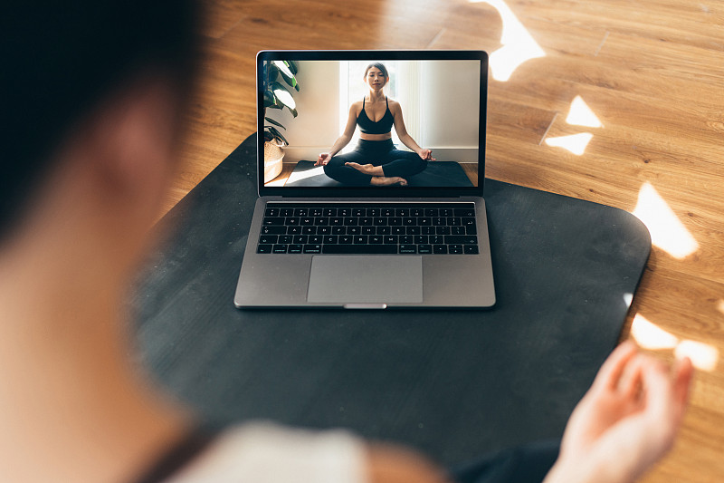 年轻女子练习瑜伽和冥想在笔记本电脑上的视频课。图片下载