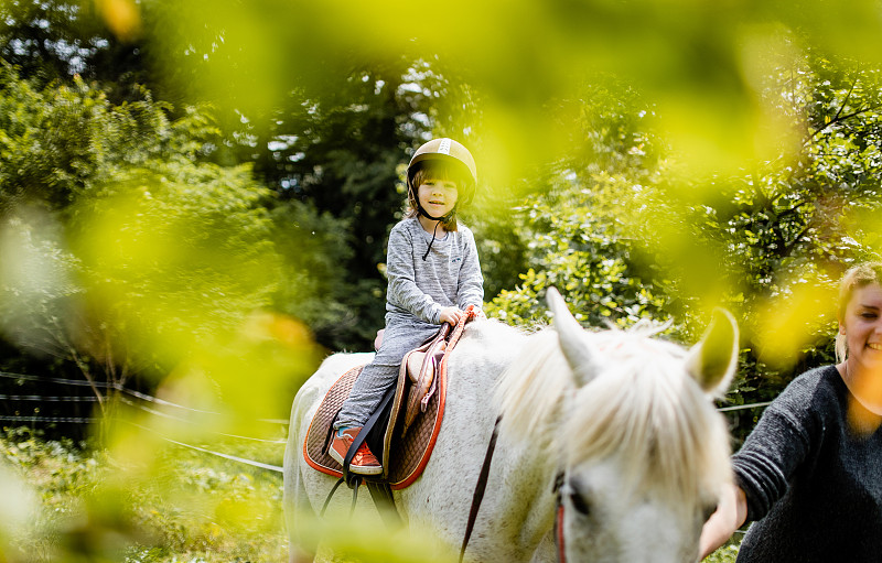 一个年轻女子教一个男孩如何骑马图片下载