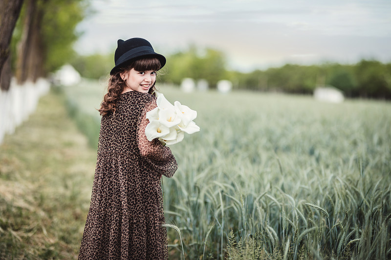美丽的女孩在她的肩膀微笑，当走在她的鲜花在她的臂弯图片素材