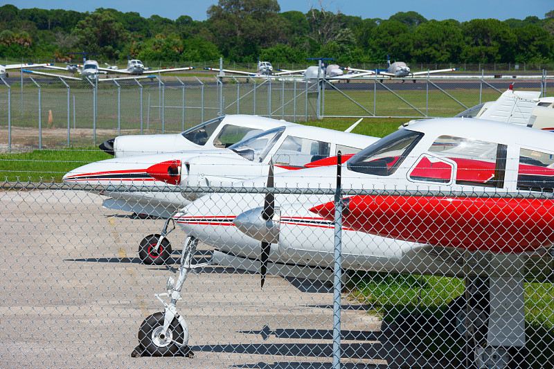 在一个阳光明媚的下午，许多小型飞机在机场的停机坪上排成一排图片下载