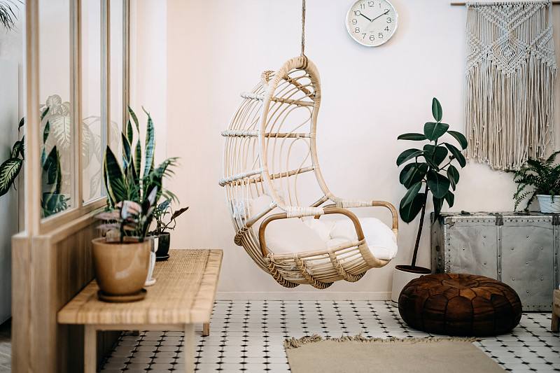 舒适的吊椅在阁楼客厅与时尚和波西米亚设计。精心设计，用各种有趣的植物装饰图片素材