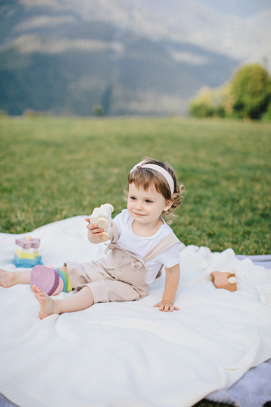 可爱的小女孩在山上的草地上玩彩色的木制玩具图片素材