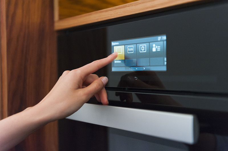 女人在厨房用手触摸烤箱的数字显示器图片素材