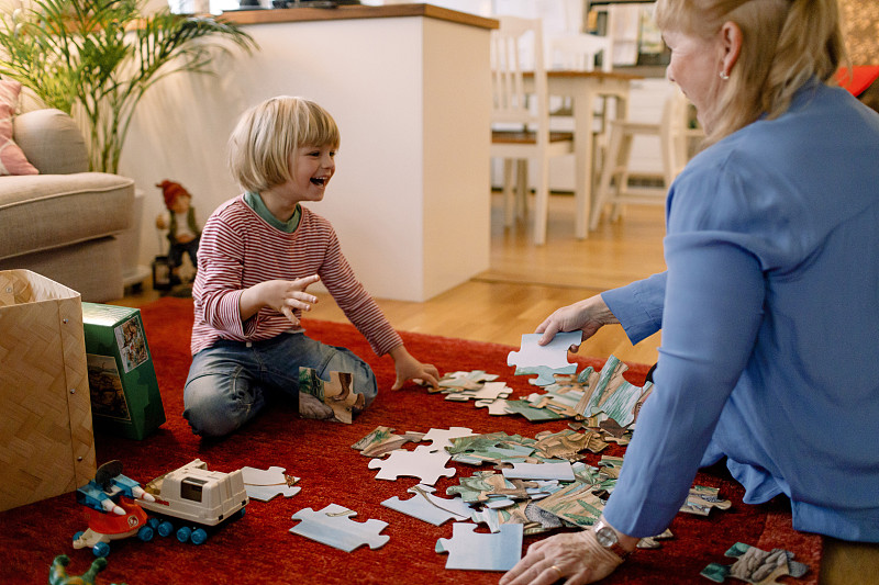 快乐的男孩和奶奶在客厅玩拼图游戏图片下载