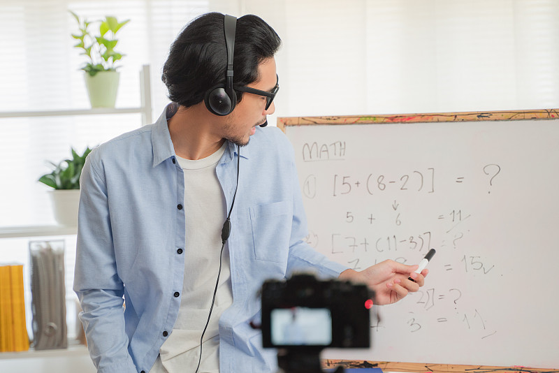 亚洲男人教数学在线，微笑的亚洲女老师说录音视频或数学课程在线家教图片素材
