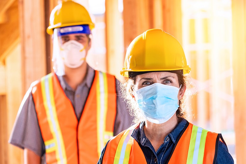 建筑工人戴着防护面罩在建筑工地工作图片下载