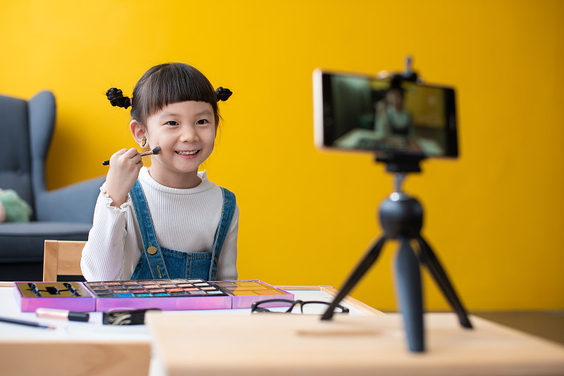 小女孩录制视频教程，如何应用孩子的化妆在直播博客上，并为她的在线时尚频道在社交媒体上录制内容图片素材