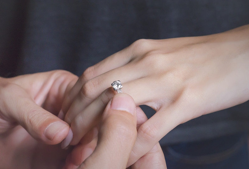 一个男人把订婚戒指戴在他女朋友的手上图片素材