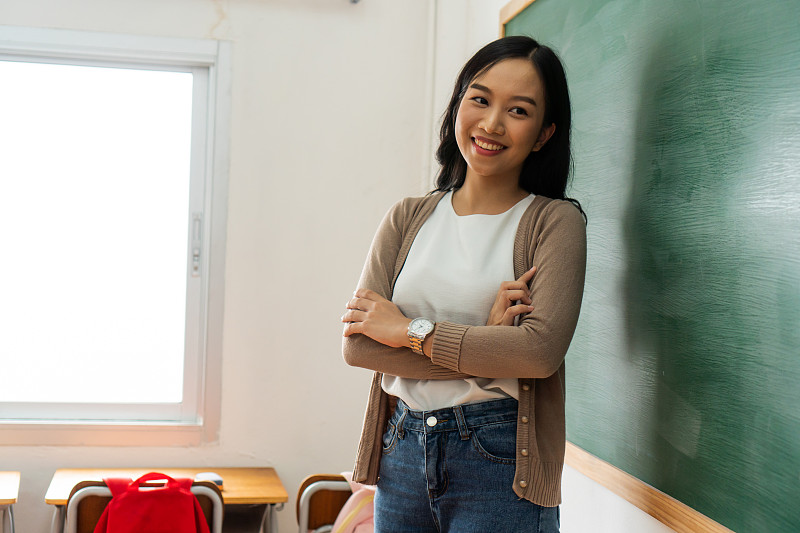 年轻的亚洲女教师在学校教室的黑板前微笑图片下载