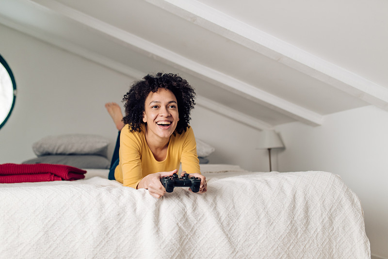 混血女人在她的床上玩游戏和玩得开心图片下载