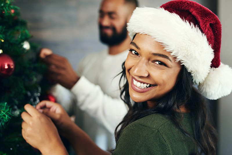 一对幸福的年轻夫妇在家里装饰圣诞树图片下载