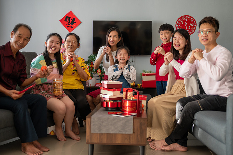 三代快乐的亚洲家庭庆祝中国新年，享受传统食物和聚会在客厅图片下载