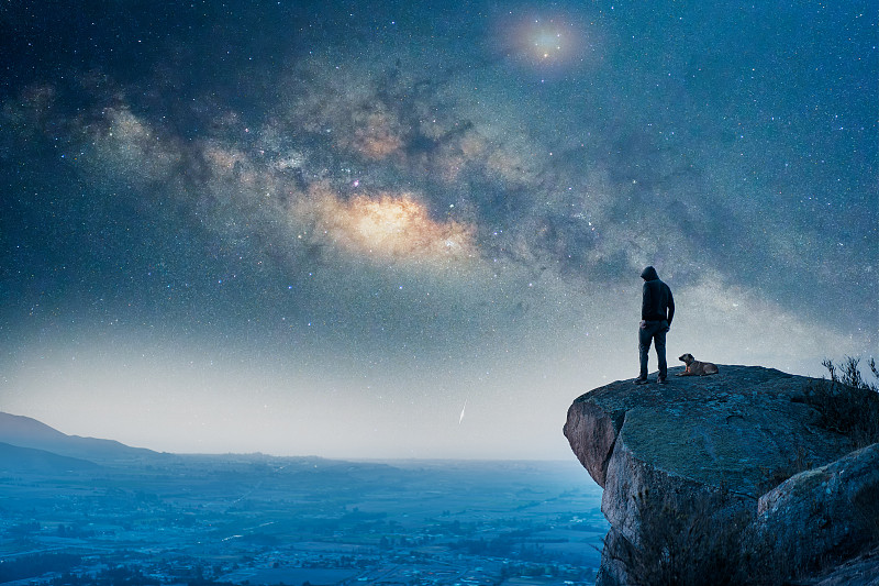 男人站在山顶，背视，与他的狗和银河的山谷图片下载