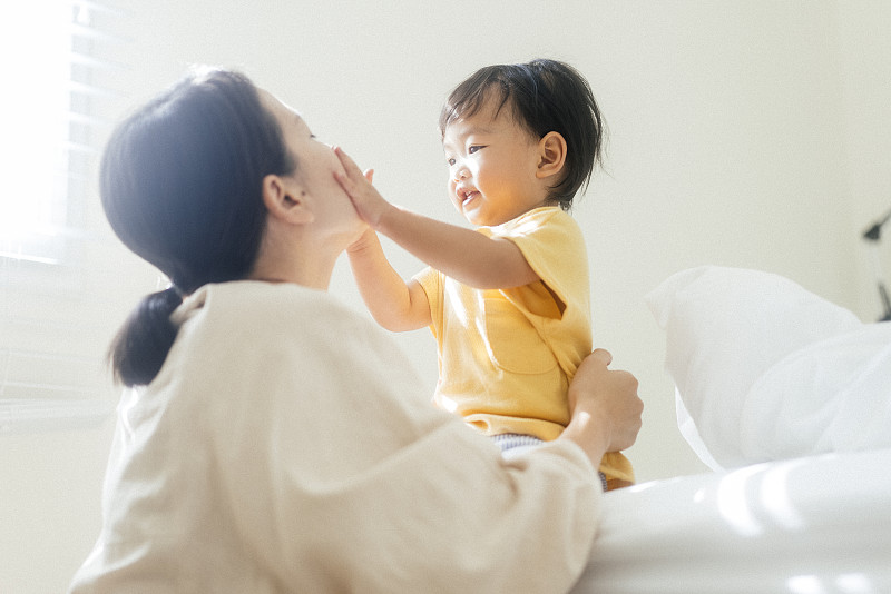 幸福时刻，在一起积极的情绪亚洲年轻的成年母亲在家里的卧室里和女儿玩耍家庭生活图片下载