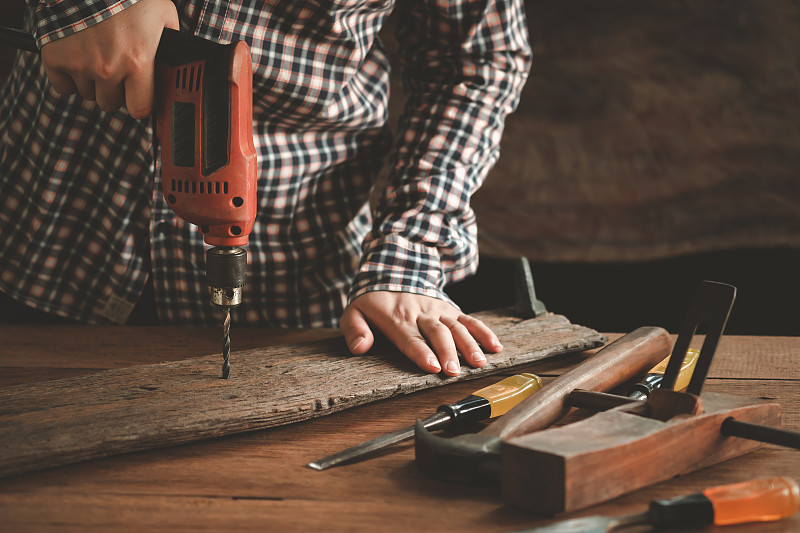 木匠用电钻钻孔，木工和木工工具在木制背景，压轴工作台，古董。图片下载