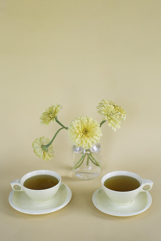 两个古董三聚氰胺杯和茶碟绿茶和一罐黄色百日菊图片下载