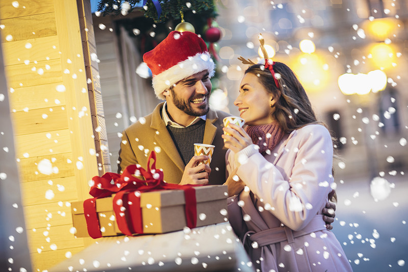 圣诞节前，年轻浪漫的情侣拿着礼盒在户外玩耍。图片下载