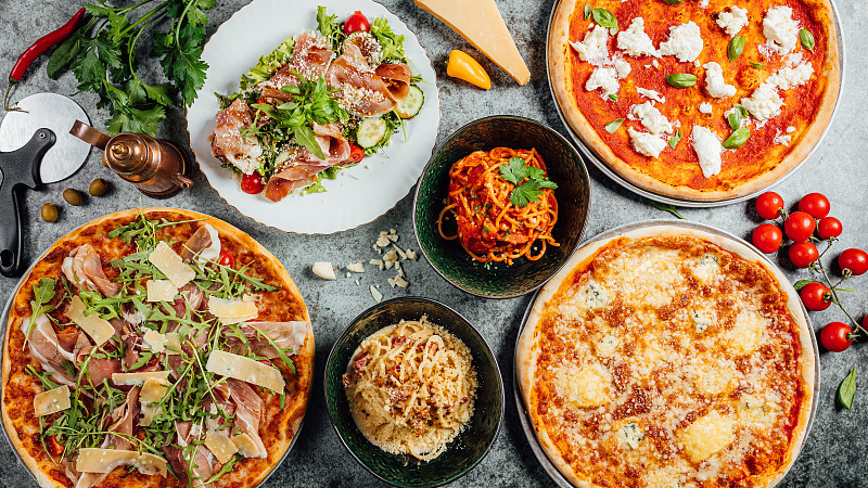 俯视图的不同类型的披萨与意大利面和蔬菜在花岗岩桌子上图片下载